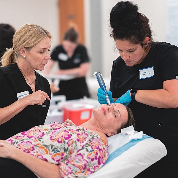 Skincare professionals performing facial treatment on client.
