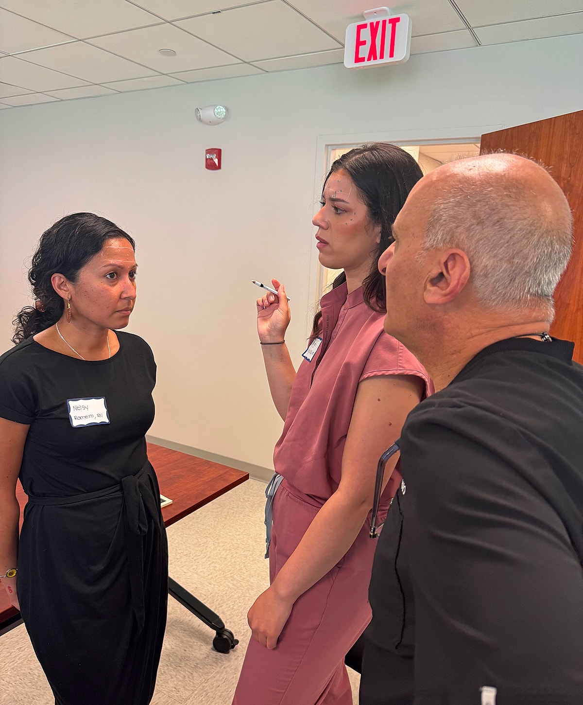 Three people engaged in serious conversation indoors.