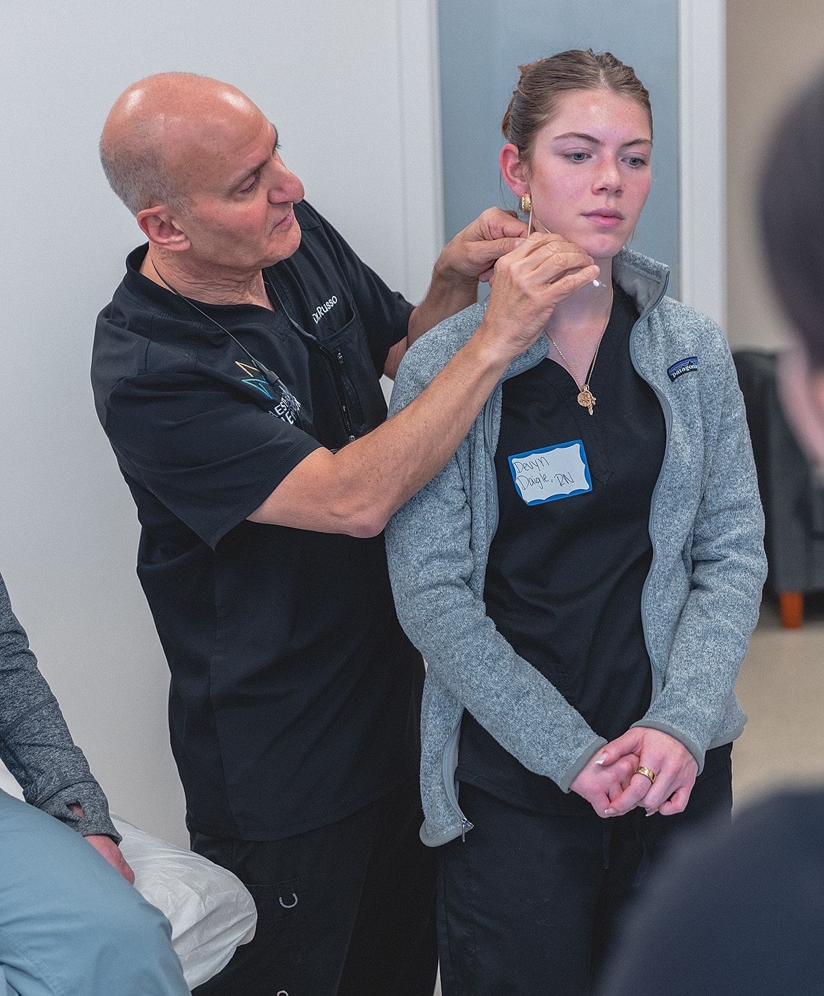 Instructor demonstrating technique on student’s ear.