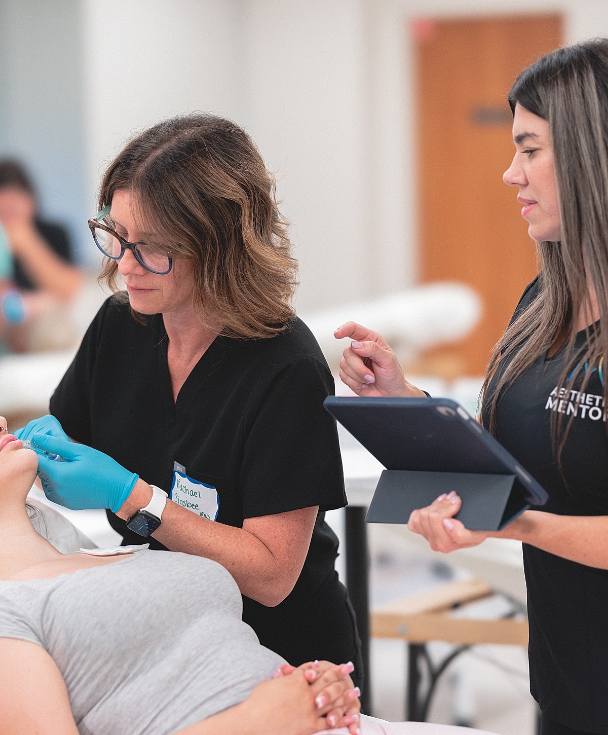 Aesthetic procedure training with two professionals present.