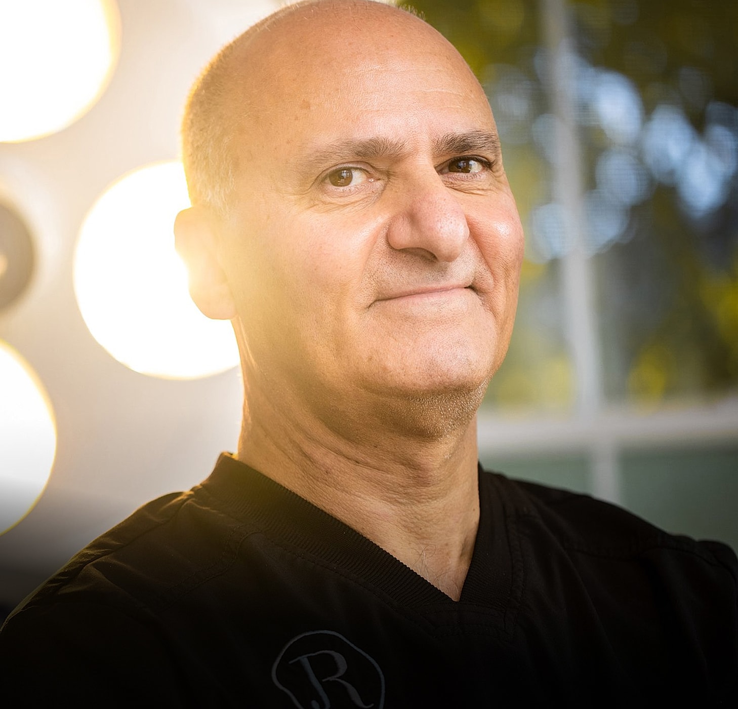 Smiling man in black shirt, soft lighting.